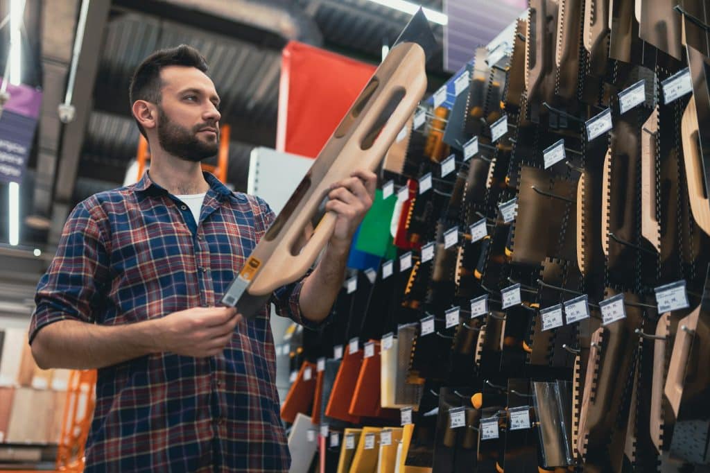 a man in the department of building materials in the store chooses a tool for wall plastering