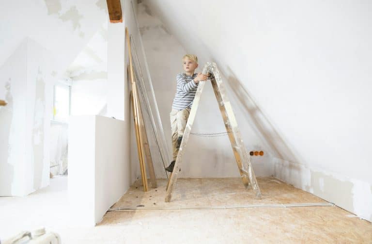 Boy standing on ladder in attic to be renovated