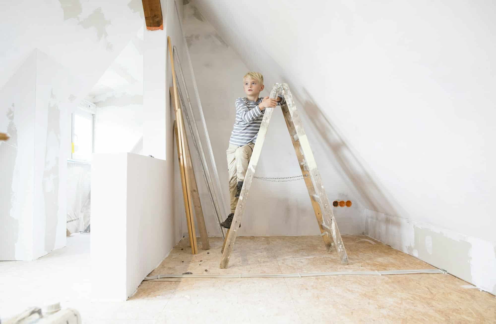 Boy standing on ladder in attic to be renovated