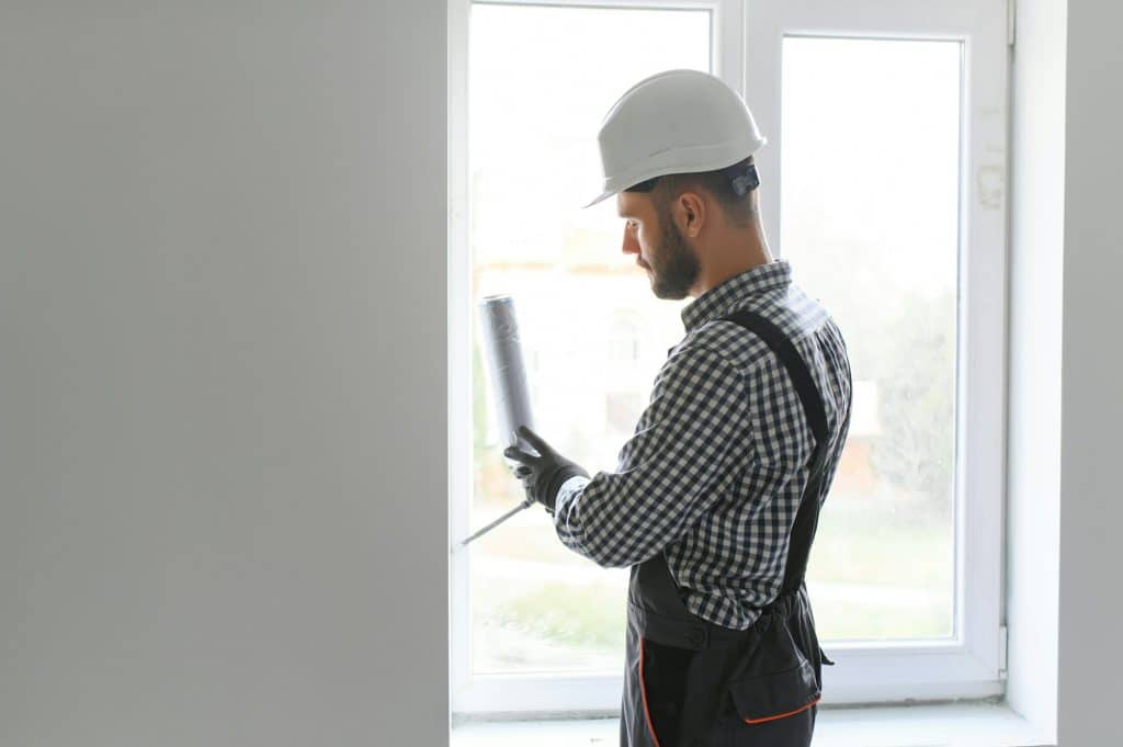 Construction worker installing window in house