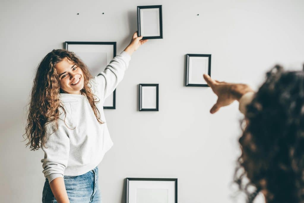 Couple hanging picture frame on wall in new house