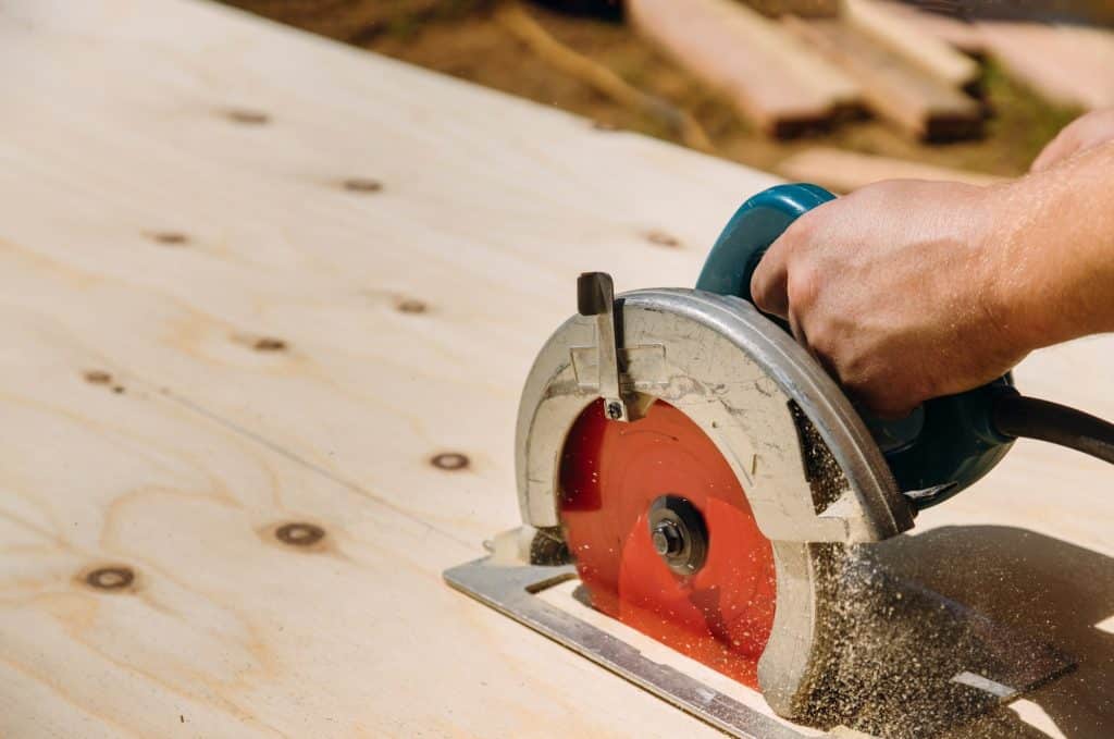 Handyman cutting plywood on hand held worm drive circular saw