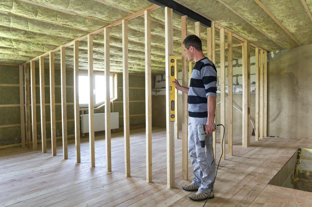 Interior of attic room with insulated ceiling and oak floor under reconstruction.