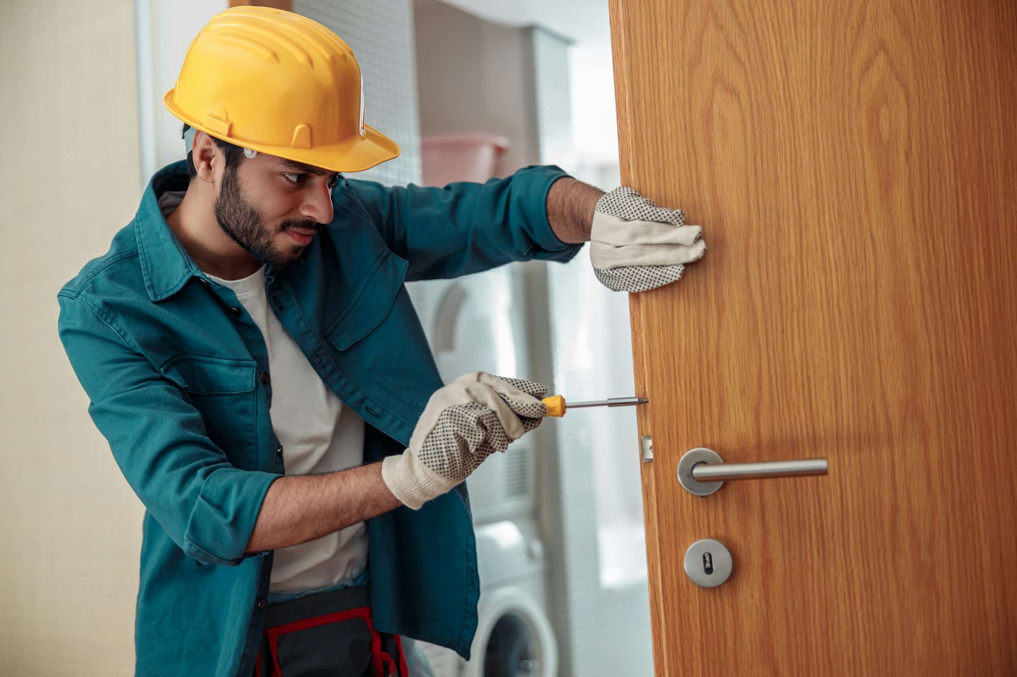 Locksmith workman in uniform installing door knob. Professional repair service