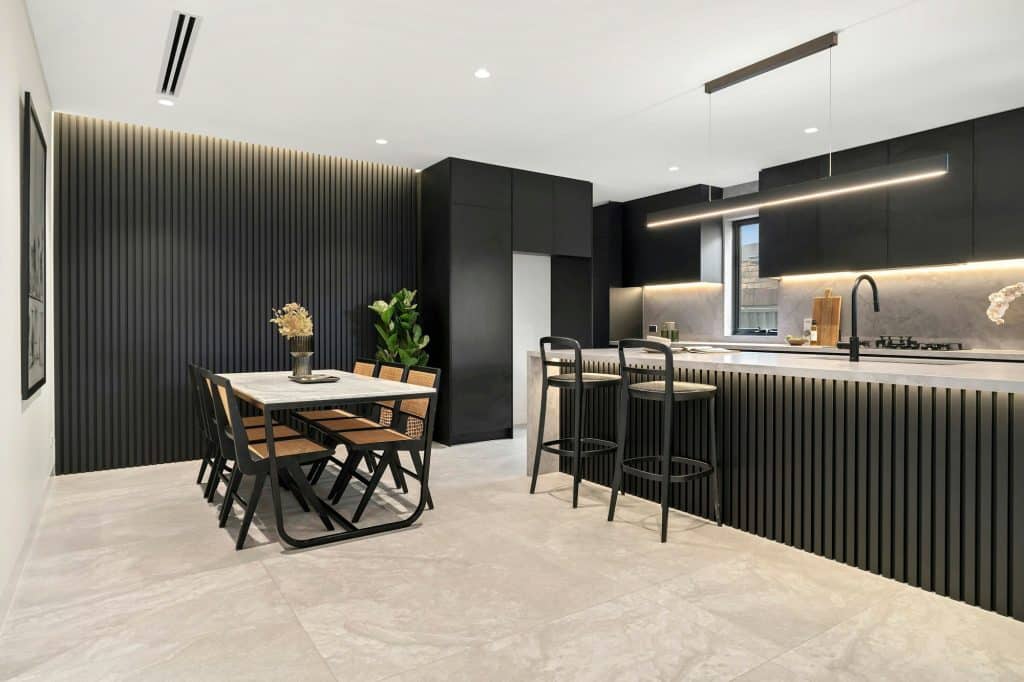 Modern kitchen and dining area with sleek black cabinetry, minimalist design, and ambient lighting.