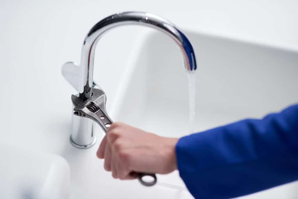 The right tool to fix a faulty faucet. Cropped shot of a plumber repairing a tap with a wrench.