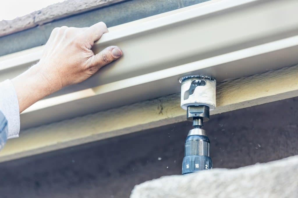 Worker Attaching Aluminum Rain Gutter to Fascia of House